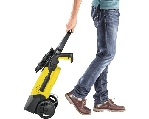 Persoană care împinge un curățător cu presiune galben cu roți.