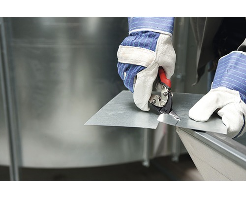 O persoană taie o tablă metalică cu o foarfecă de tablă.