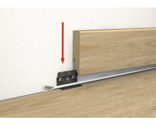 Ilustrație a montării unei plinte de lemn cu canal de cablu și o săgeată roșie care indică direcția de montare.