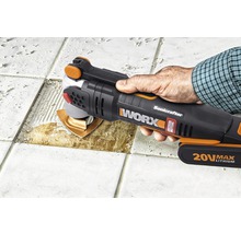 Un bărbat folosește o unealtă electrică oscilantă marca Worx pentru a îndepărta plăcile de pe o podea placată cu gresie.