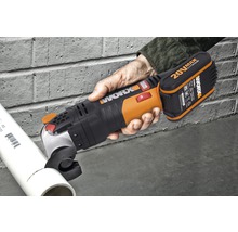 O mână ține un mini ferăstrău circular cu acumulator în timp ce taie o țeavă.