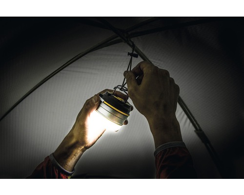 O persoană fixează o lampă de camping în cort.