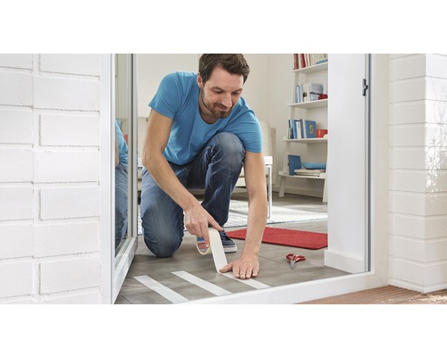 Bărbat aplicând bandă adezivă de mascare pe podea pentru lucrări de renovare