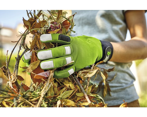 O mână cu o mănușă de grădinărit apucă frunze și crengi.