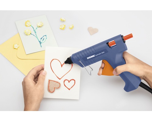 Persoană care folosește un pistol de lipit pentru a face felicitări
