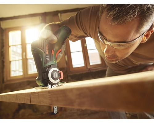 Un bărbat taie o scândură de lemn cu un ferăstrău pendular cu acumulator Bosch