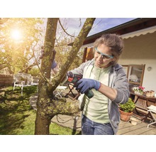 Femeie taie copac cu un ferăstrău de crengi cu acumulator în grădină