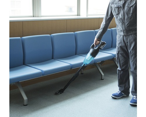 O persoană folosește un aspirator fără fir într-o zonă de așteptare.