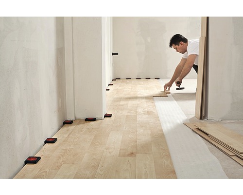 Montarea laminatului cu unelte și distanțiere într-o cameră.