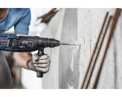 Bărbat găurește un perete de beton cu un ciocan rotopercutor