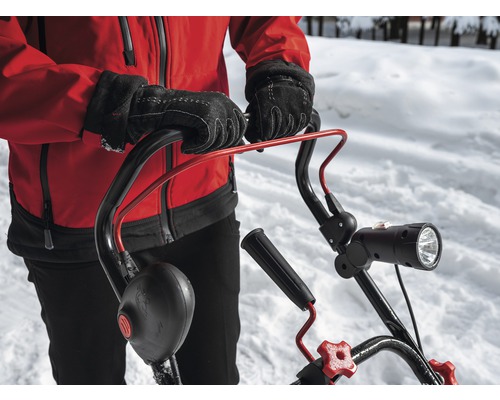 Persoană cu mănuși care operează o freză de zăpadă