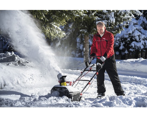 Bărbat care îndepărtează zăpada cu o freză de zăpadă în timpul iernii