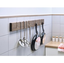 Ustensile de bucătărie și tigăi atârnate de o bară de bucătărie pe perete.