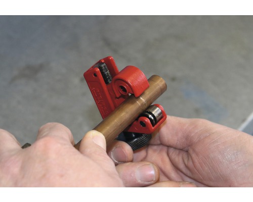 Un tăietor de țevi de cupru taie o țeavă de cupru.