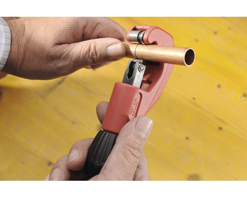 O țeavă de cupru este prelucrată cu un tăietor de țevi.