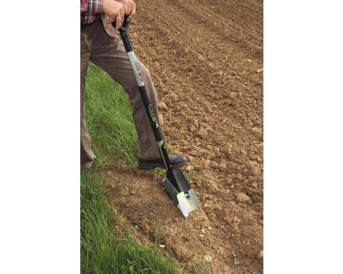 O persoană folosește un hârleț în grădină.