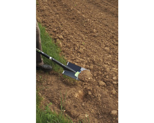 O persoană sapă un câmp cu un hârleț.