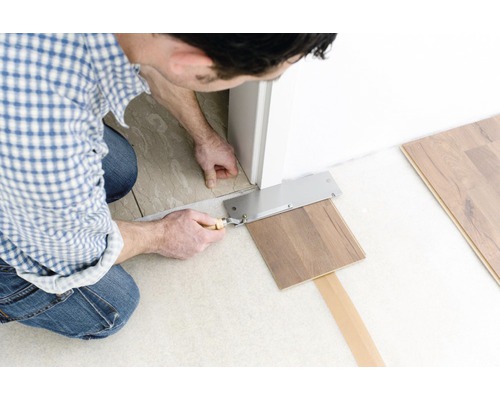 Bărbat taie laminatul cu un ferăstrău la tocul ușii