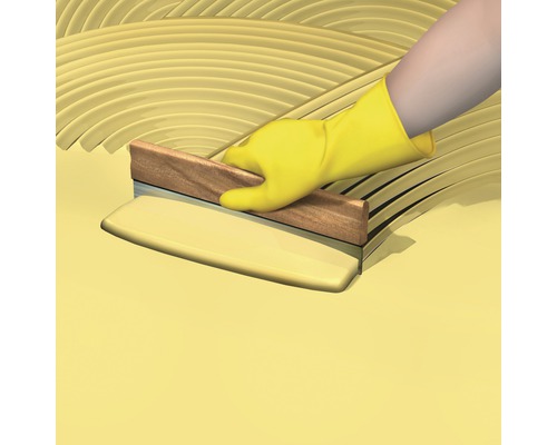 Aplicarea adezivului cu o mistrie cu crestături de către o persoană cu mănuși de protecție.