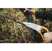 Persoană taie o ramură cu un fierăstrău manual de la Fiskars