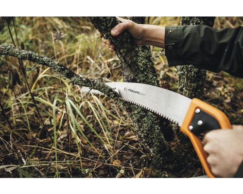 Persoană taie o ramură cu un fierăstrău manual de la Fiskars