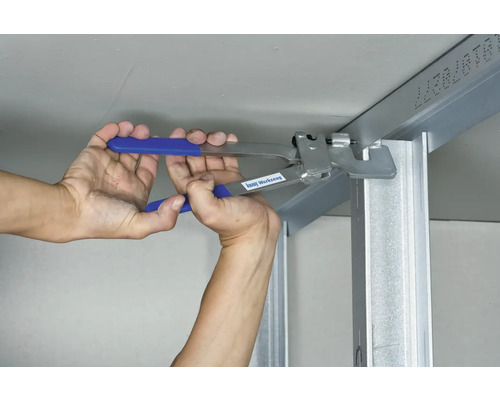 O persoană fixează un profil metalic de un tavan cu un clește.