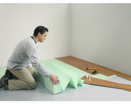 Bărbat montează podea laminată cu izolație fonică