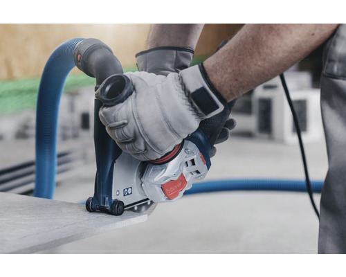 O freză de canelat în pereți în acțiune la tăierea pietrei, manevrată de o persoană cu mănuși.