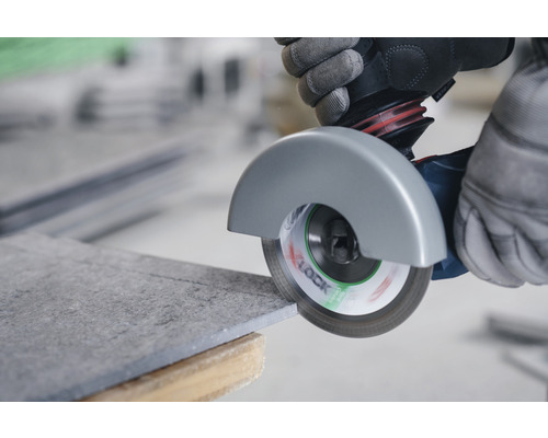 O placă de faianță este tăiată cu un polizor unghiular.