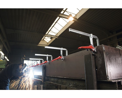 Un muncitor sudează metal cu cleme de tâmplărie într-un atelier.