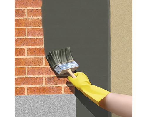 Zugrăvirea unui zid de cărămidă cu o pensulă și o mănușă de protecție