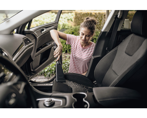 Femeie aspiră scaunele auto cu aspiratorul