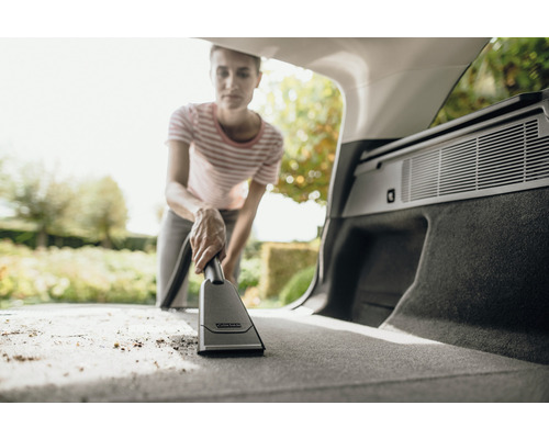 Femeie aspiră portbagajul mașinii cu aspiratorul