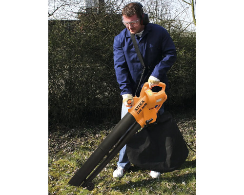 Un bărbat folosește un aspirator de frunze în grădină