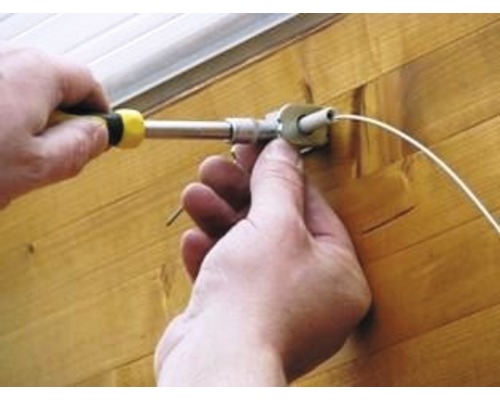 O persoană montează o jaluzea cu o șurubelniță.