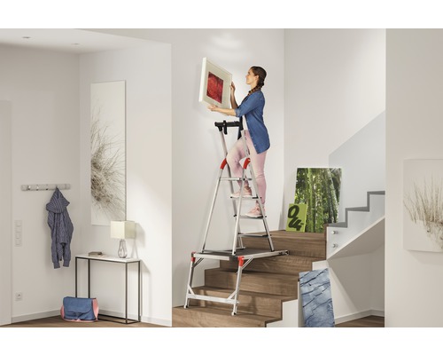 Femeie care atârnă o fotografie cu o scară în hol