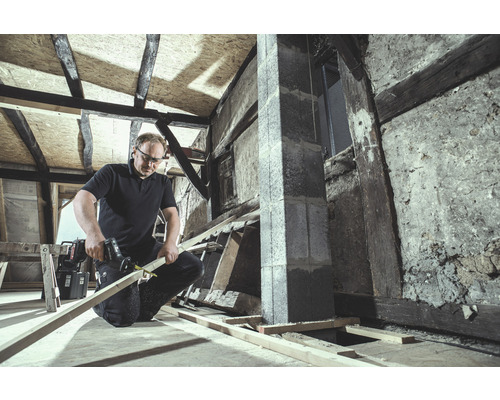 Artizan taie lemn cu un ferăstrău sabie într-o cameră nerenovată.