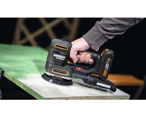 Șlefuitor cu acumulator utilizat pe o suprafață din lemn.