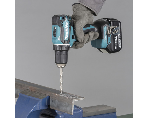 Mașină de găurit și înșurubat cu acumulator Makita care găurește o bucată de metal fixată într-o menghină