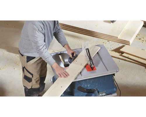 O persoană taie o scândură de lemn cu un ferăstrău circular de masă.