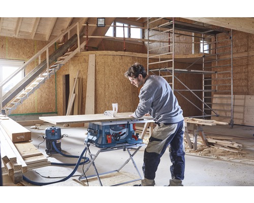 Un bărbat lucrează cu un fierăstrău de masă într-o clădire în construcție.