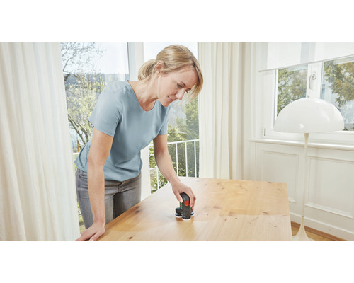 Femeie șlefuind un blat de masă cu o șlefuitoare