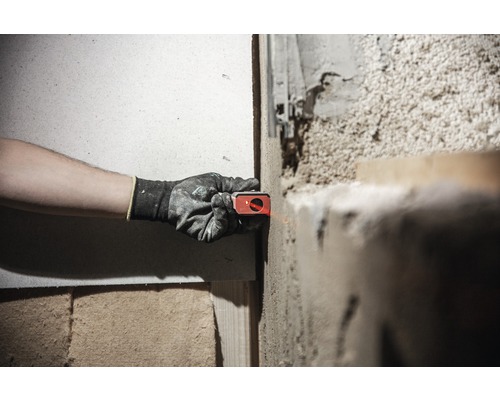 O persoană folosește o nivelă laser pe un perete pentru a alinia un proiect.