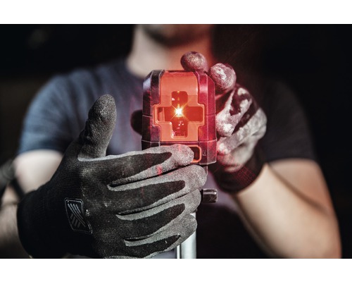 O persoană ține în mână un laser de construcții cu raze laser roșii.