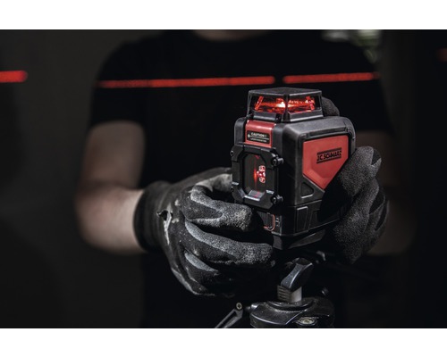 Persoană care ține un laser cu linii încrucișate JC Schwarz pe un trepied