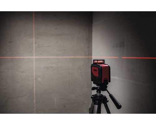 Laser cu linii încrucișate roșu pe un trepied proiectând linii pe un perete