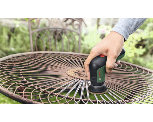 Perie de sârmă folosită pe o masă de grădină din metal