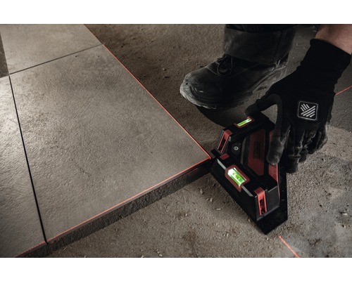 O persoană montează plăci folosind un laser liniar pentru aliniere.