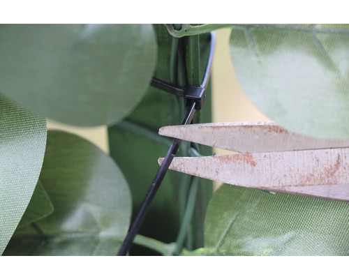 O foarfecă taie o legătură de cablu pe o plantă artificială.