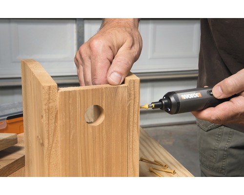 O persoană folosește o șurubelniță pentru a asambla o căsuță din lemn pentru păsări.